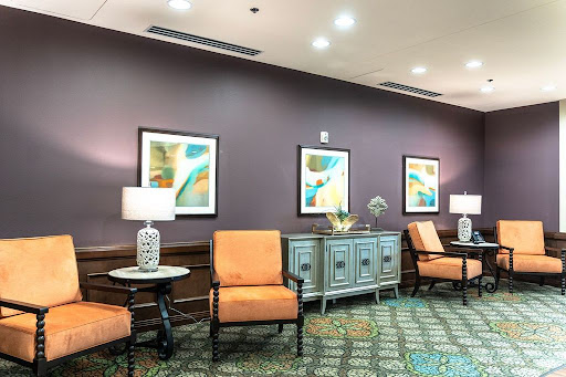 A cozy lobby area featuring orange chairs, decorative art pieces on the wall, and stylish lamps.
