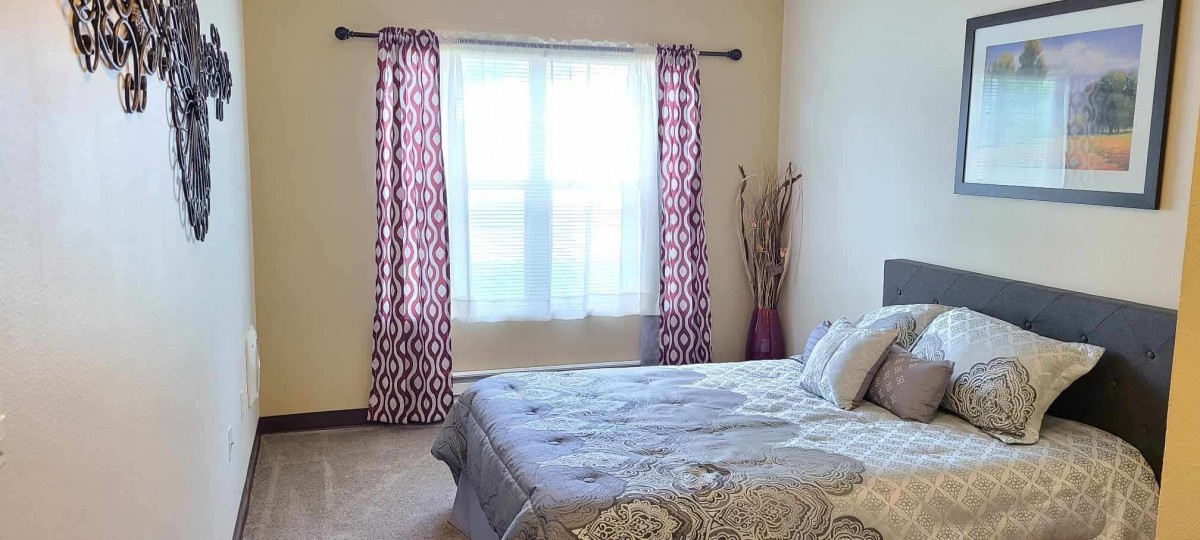 A minimalist bedroom with patterned curtains and a neatly made bed.