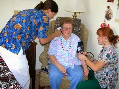 Healthcare professionals conducting a medical examination for an elderly patient in a home setting.