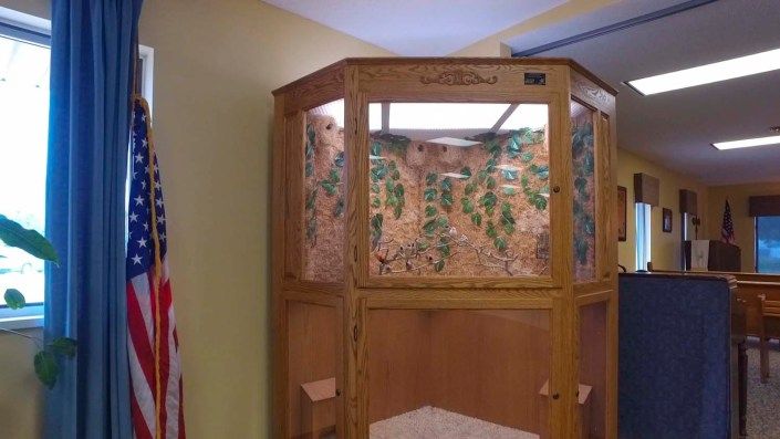 A wooden indoor birdcage or aviary with decorative elements.