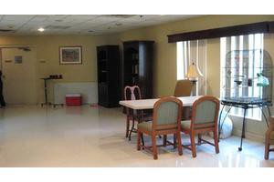 A spacious dining room with a table and chairs, adorned with bookshelves and a window for natural light.