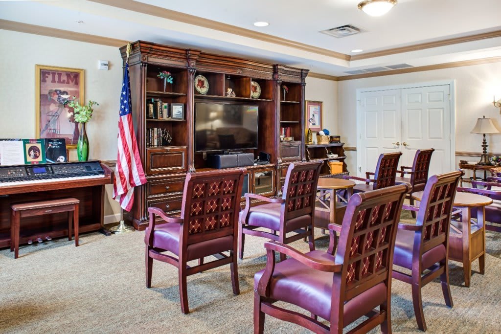 A conference room with a television, bookshelf, and several chairs arranged for a meeting.