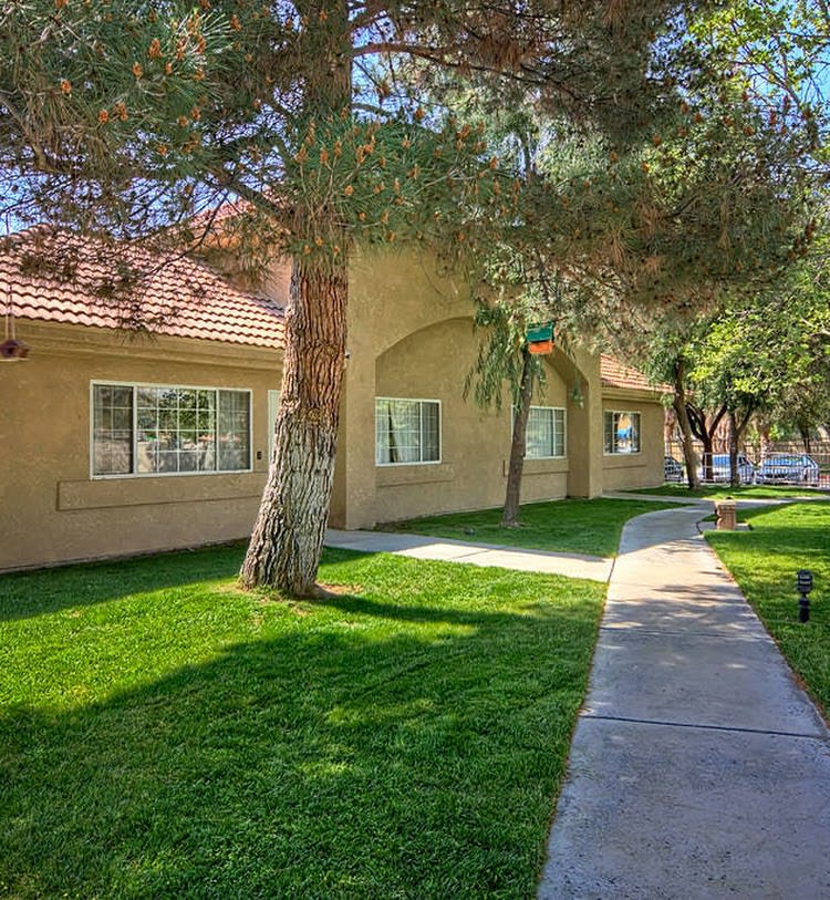 A residential building with a well-maintained lawn and surrounding trees.