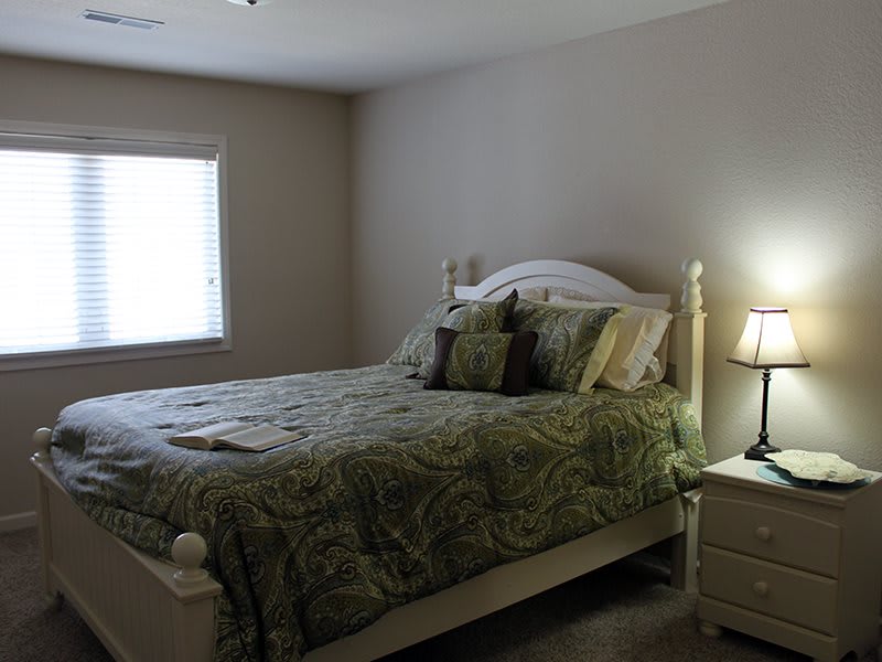 A cozy bedroom with a bed, nightstand, and lamp.