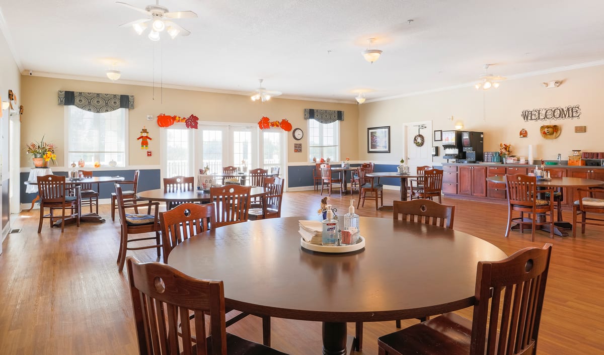 A spacious dining room with multiple tables and chairs, decorated with colorful accents.