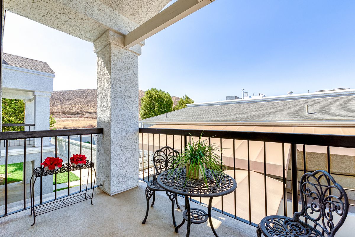 A scenic balcony with a small table and chairs, featuring decorative potted plants and overlooking the surroundings.