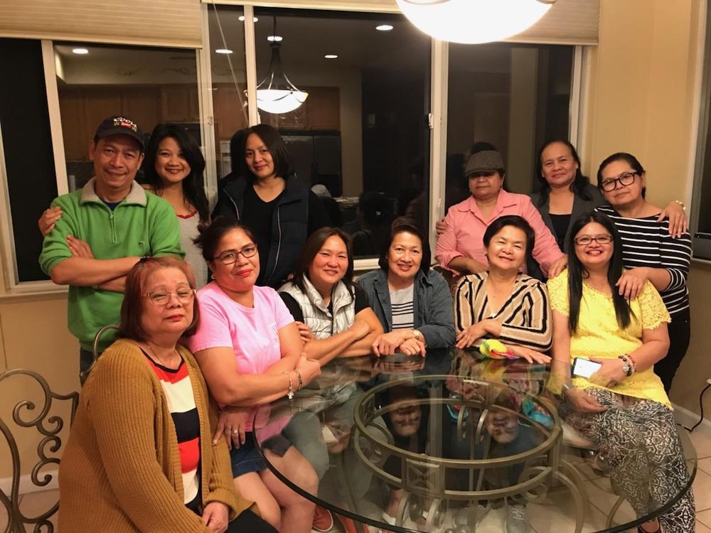 A group of people gathered around a table indoors, smiling for the camera.