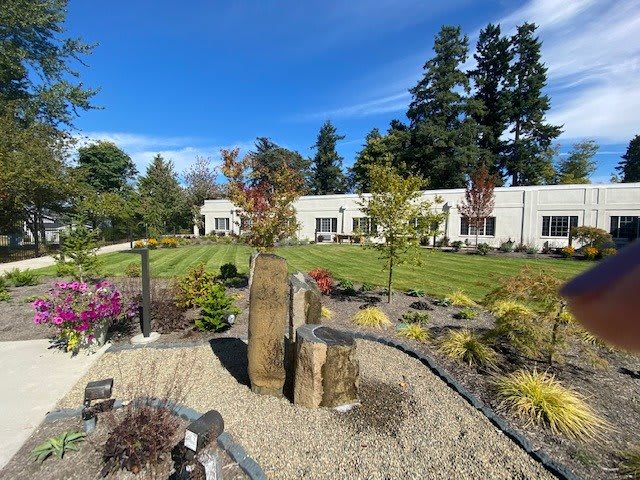 A beautifully landscaped garden with a building in the background under a clear blue sky.