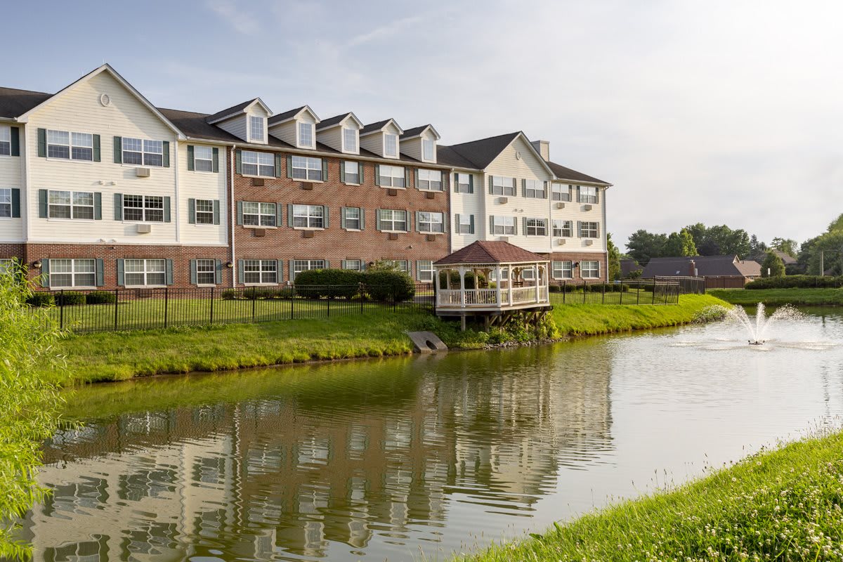 A picturesque building by a tranquil pond with lush greenery surrounding it.