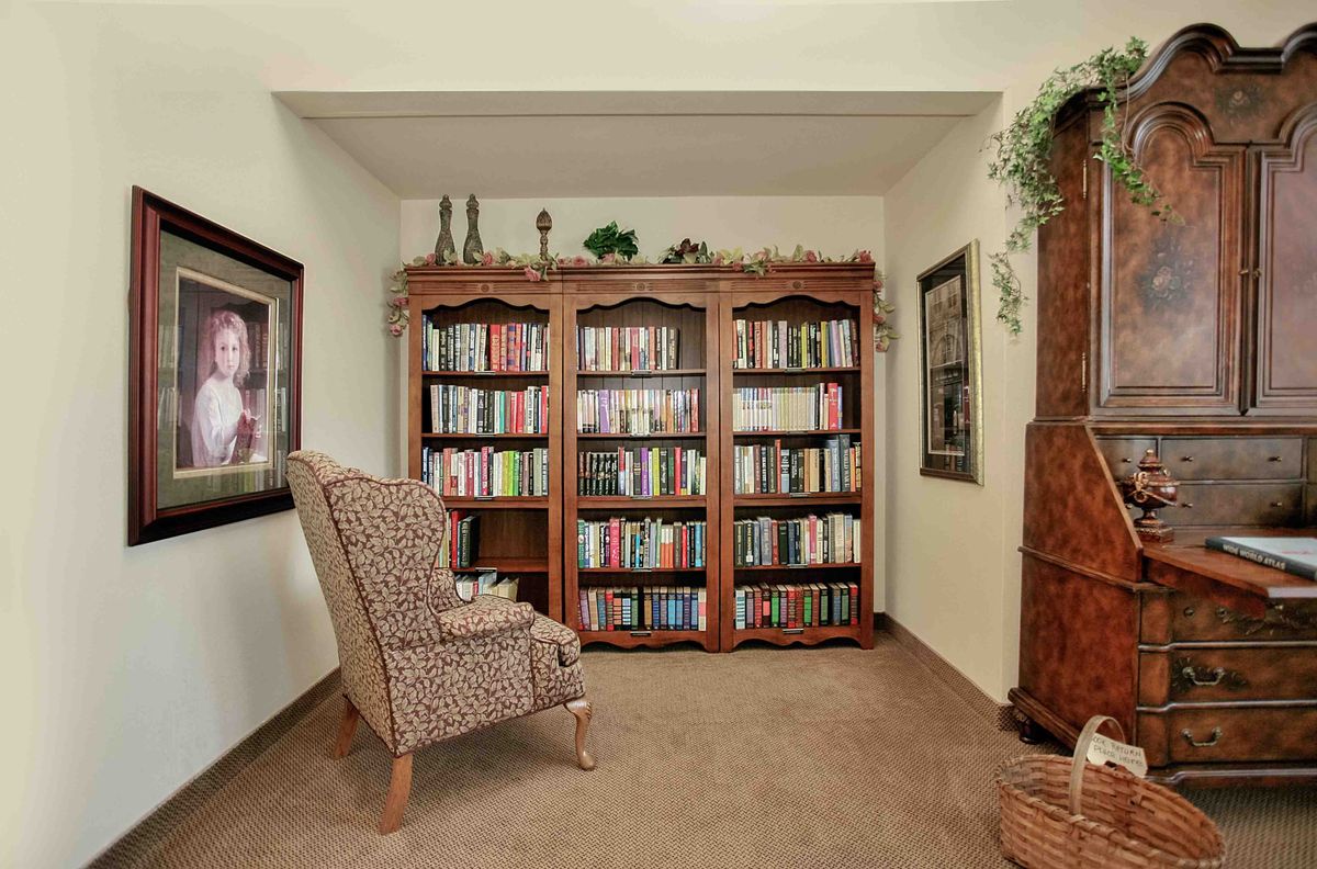 A cozy home library with a comfortable armchair and bookshelves filled with books.