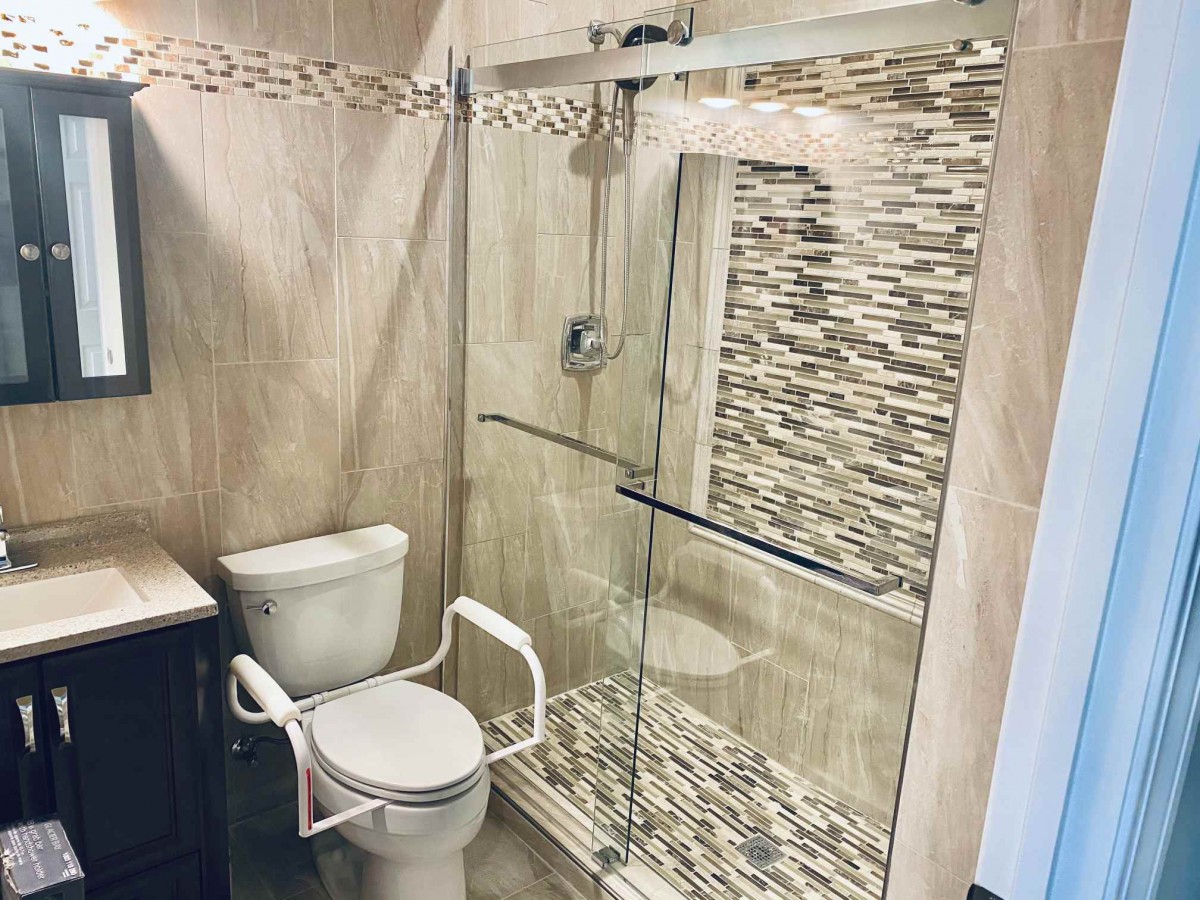 A modern bathroom with a glass-enclosed shower and an accessible toilet.