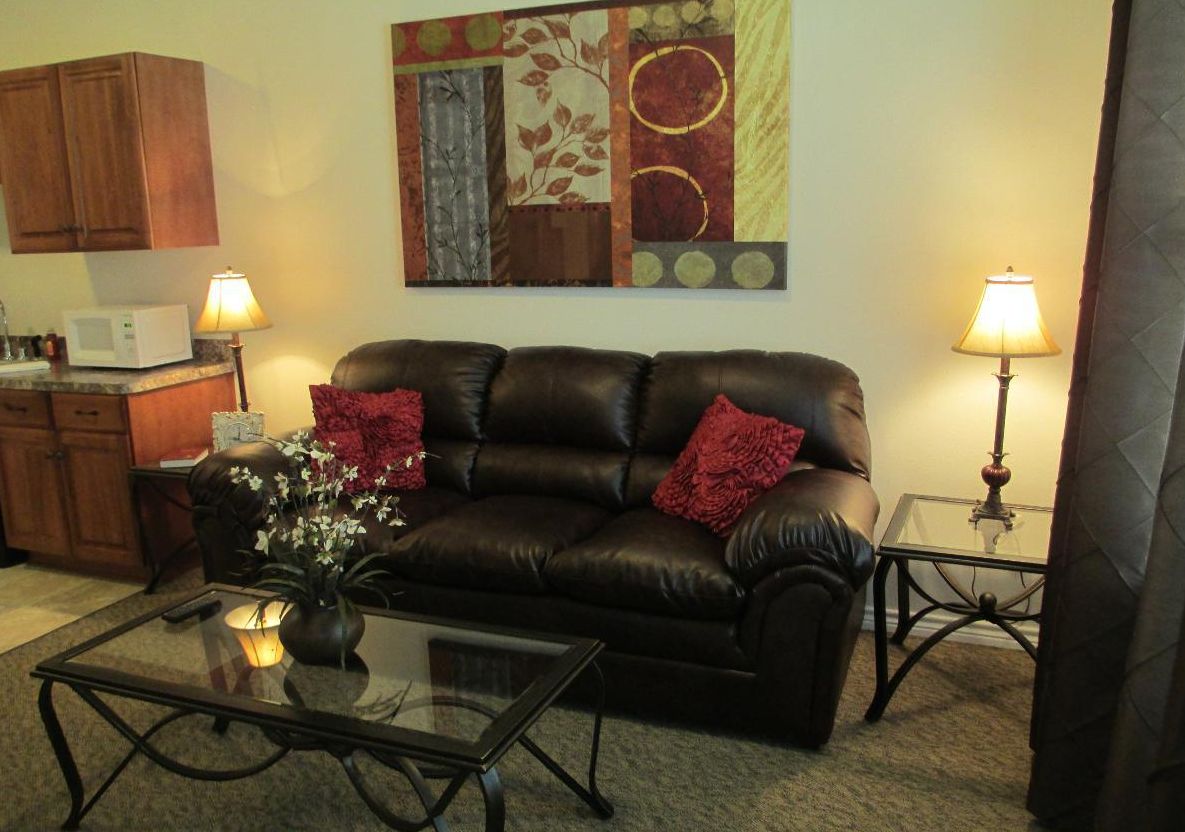 A cozy living room with a leather sofa, glass coffee table, and decorative wall art.