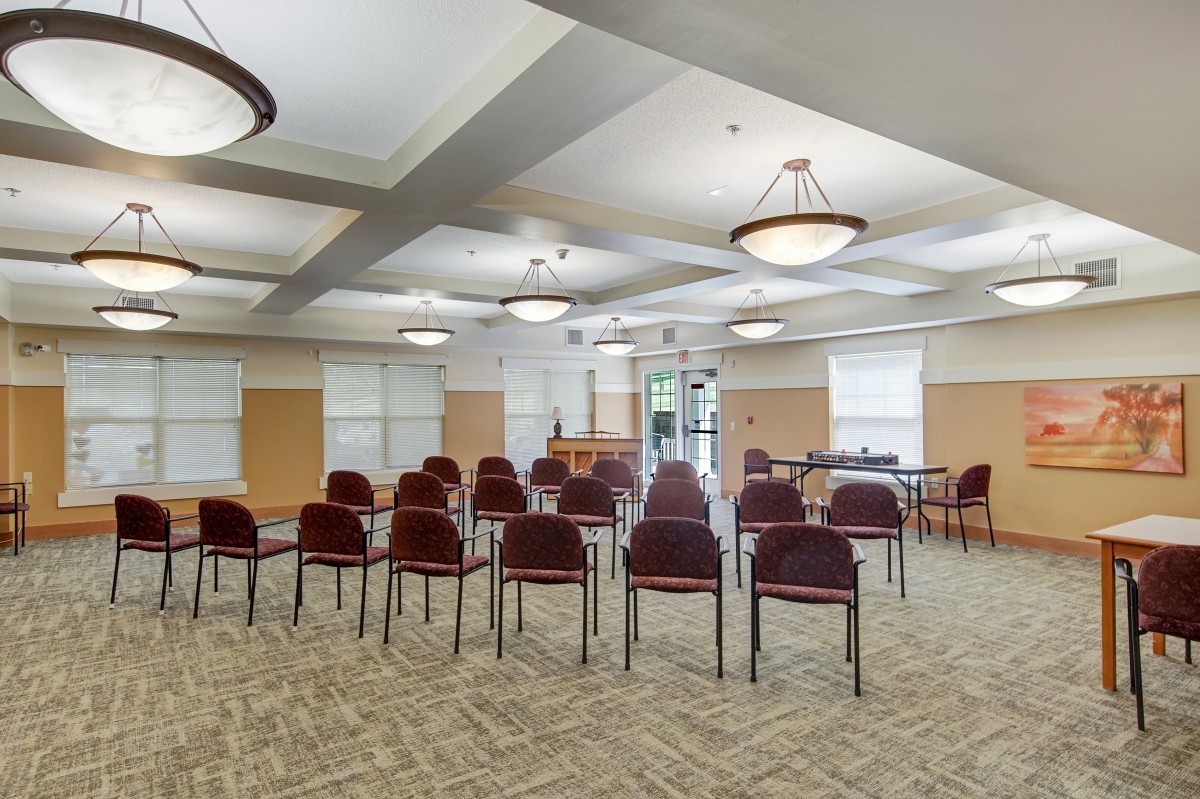 An empty conference room setup with rows of chairs and ceiling lights.