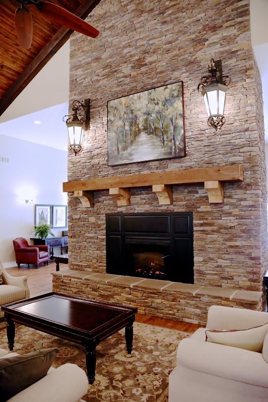 A cozy living room featuring a stone fireplace with artwork and elegant furnishings.