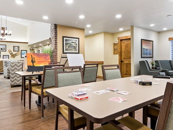 A well-lit meeting room with a conference table, chairs, and a whiteboard, decorated with artwork on the walls.