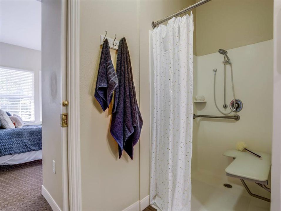 A modern bathroom with towels hanging and a shower equipped with handrails.
