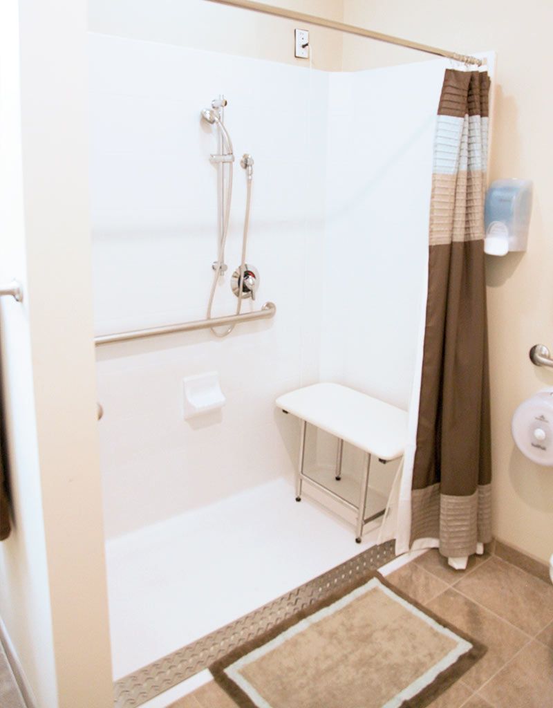 A handicap accessible bathroom with a shower seat and grab bars.