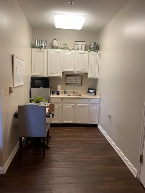 A compact kitchen setup with white cabinets and wooden flooring.