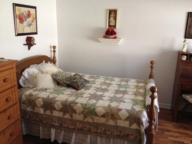 A cozy bedroom with a traditional quilt on the bed and decorative elements on the walls.