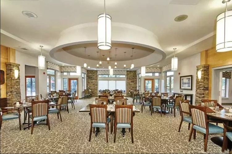 A spacious dining room with elegant lighting and neatly arranged tables and chairs.