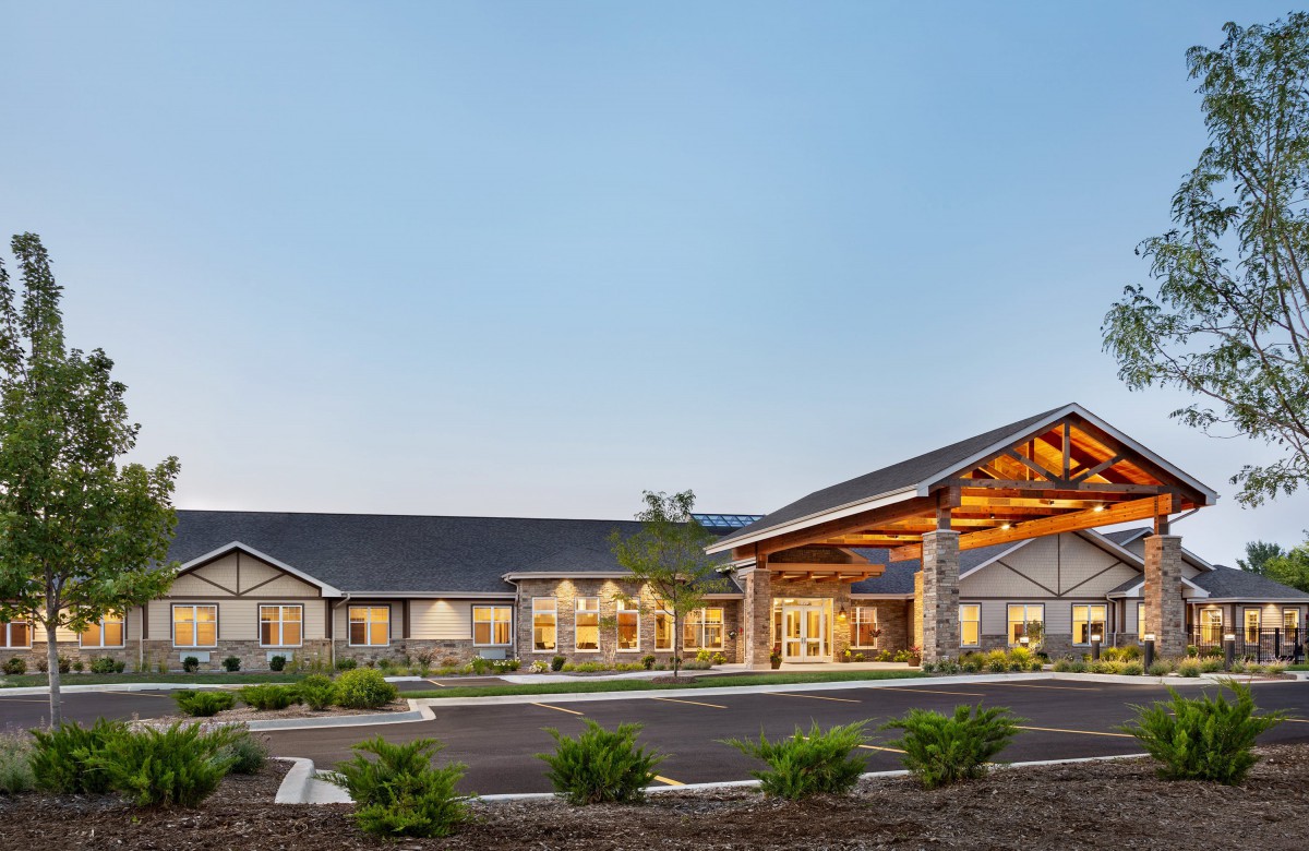 A modern residential building with a spacious driveway and landscaped surroundings at dusk.