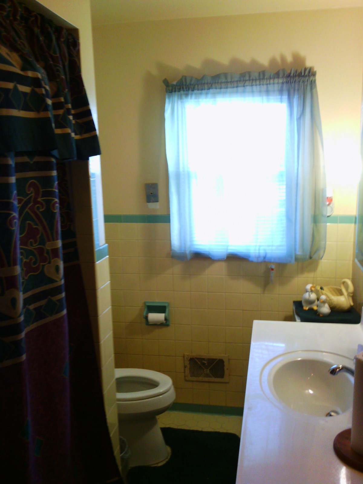 A small bathroom with a window, toilet, and sink.