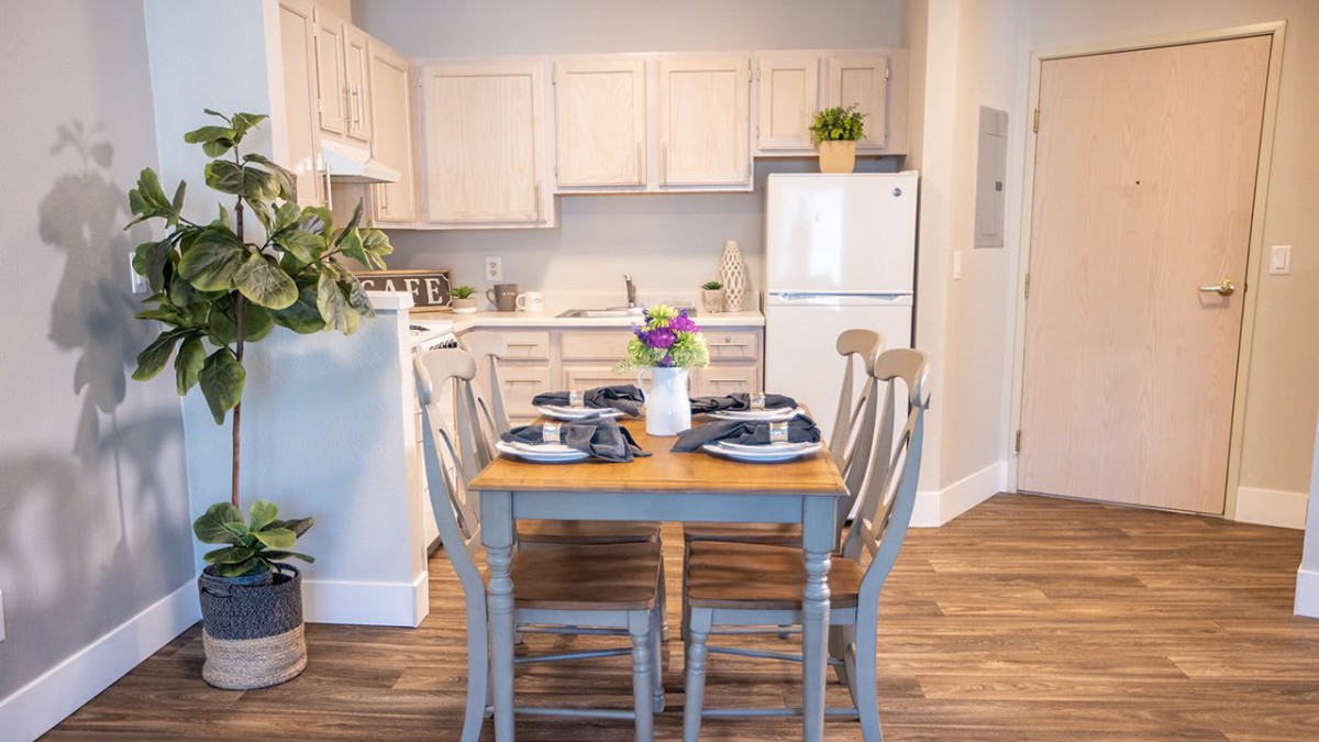 A cozy kitchen with a neatly set dining table and white cabinets.