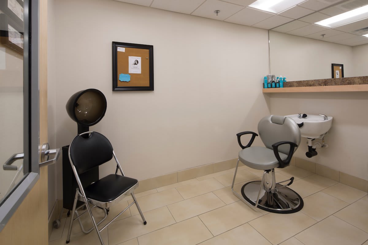 A small beauty salon room with a chair, hair dryer, and toiletries.