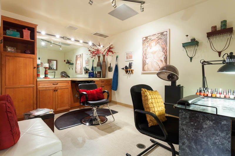 A stylish hair salon interior with well-arranged furniture and a large mirror reflecting the workspace.