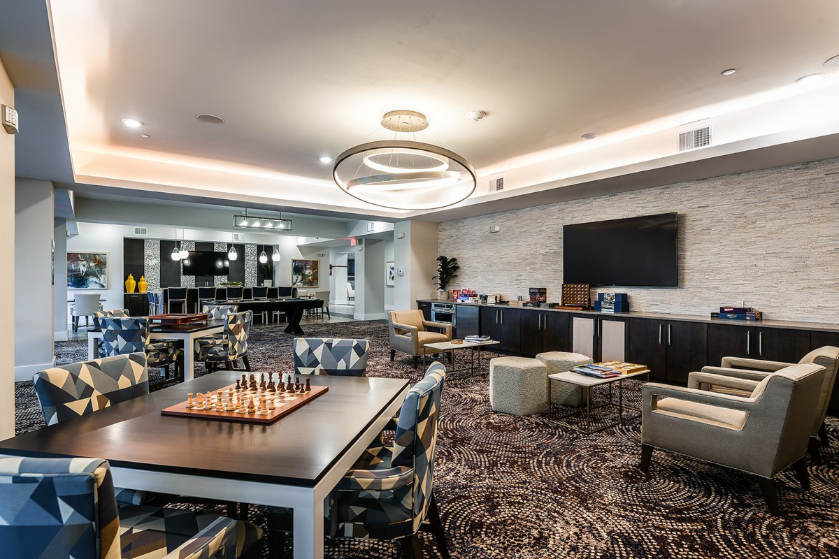 A modern lounge area with comfortable seating, a chess board, and a large television.