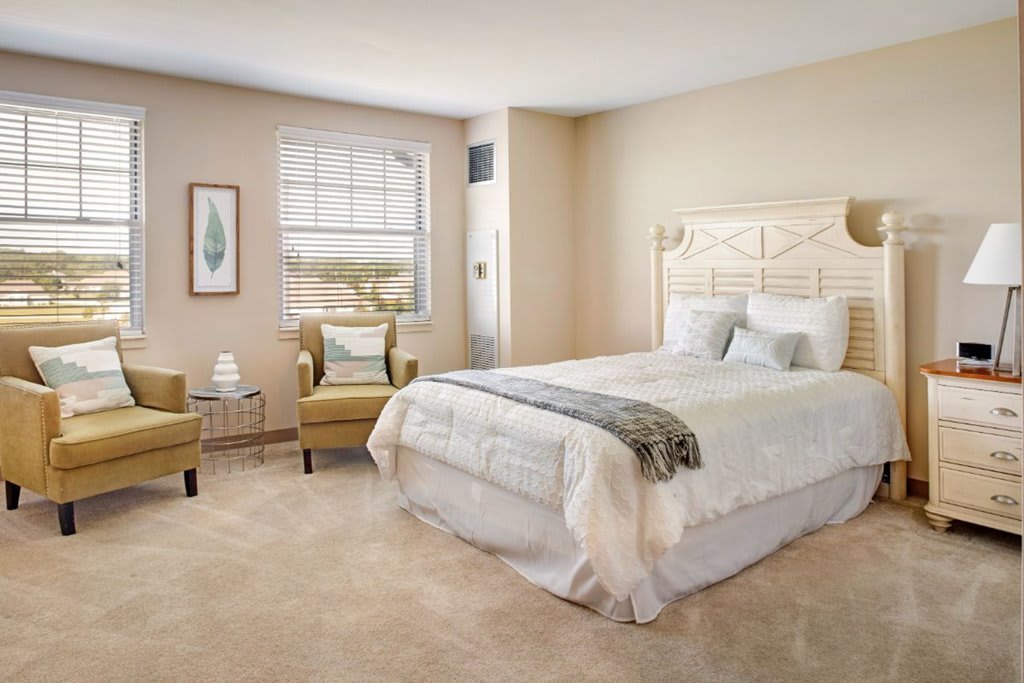 A cozy bedroom with a large bed, comfortable chairs, and soft lighting.