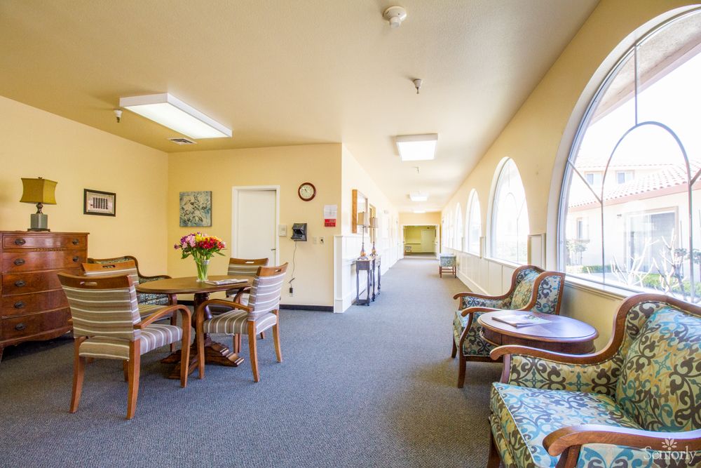 A bright, welcoming hallway with seating arrangements and large windows.