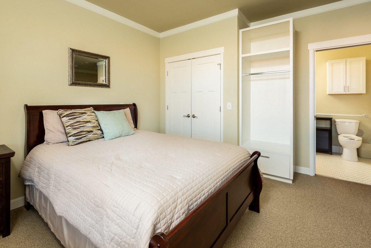 A minimalist bedroom with a neatly made bed and an open closet.