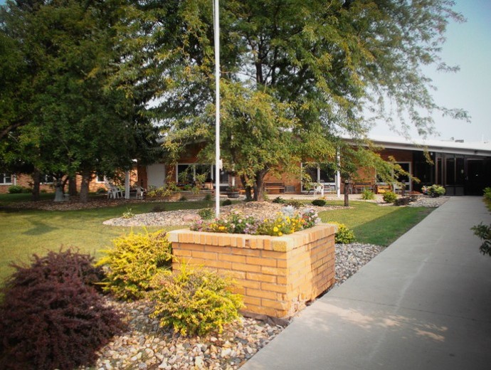 A building surrounded by a landscaped garden with a sidewalk and trees.