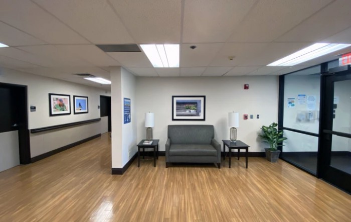 A waiting area with a sofa, two side tables with lamps, and artwork on the walls in an office setting.