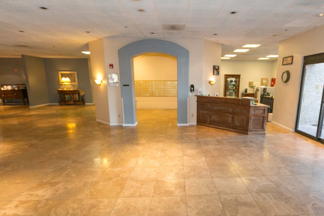 A spacious lobby area featuring a reception desk and an archway, with tile flooring and ambient lighting.