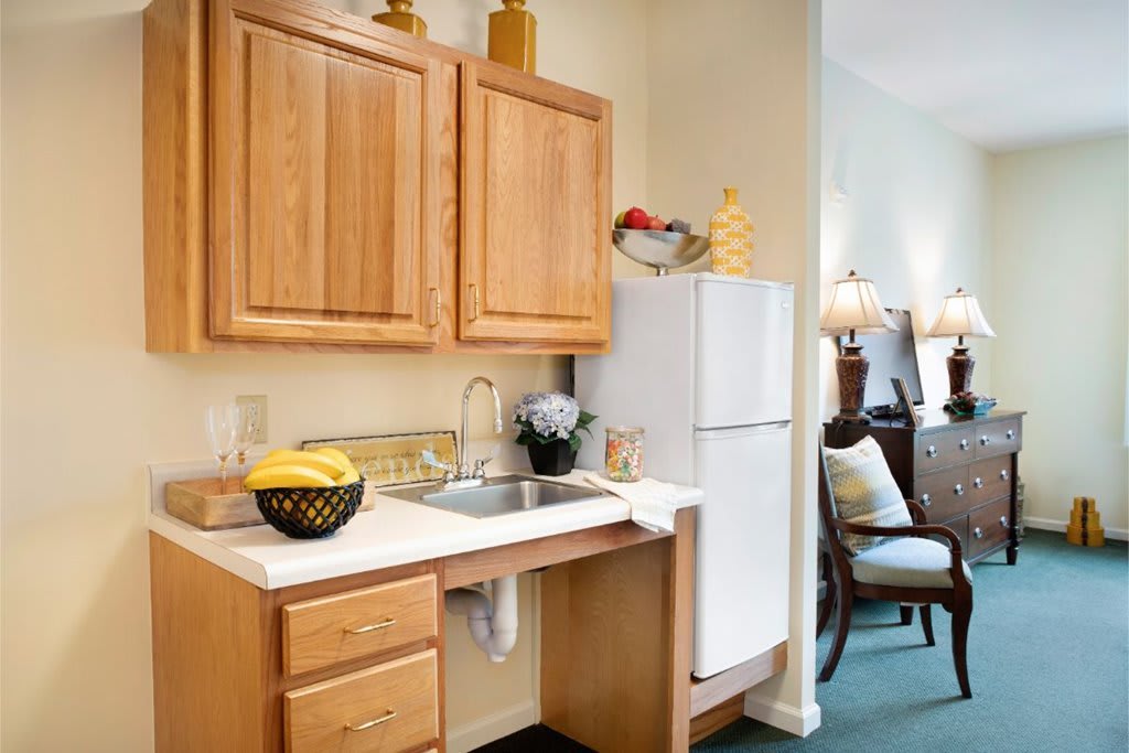 A compact kitchen area with wooden cabinets, a sink, and a refrigerator.