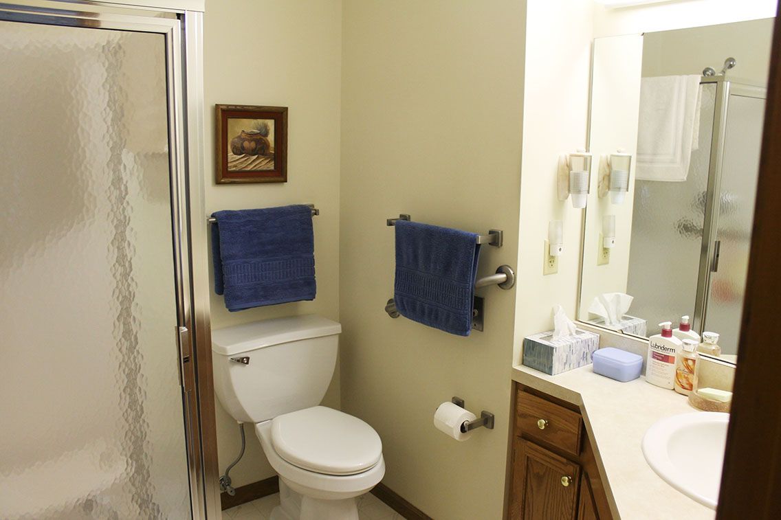 A neatly organized bathroom with blue towels and a framed picture.