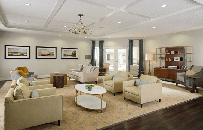 A modern living room with elegant furnishings, featuring sofas, armchairs, a chandelier, and a central coffee table.