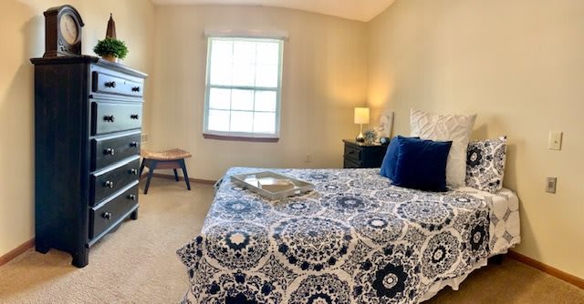 A cozy bedroom with patterned bedding and a small nightstand.