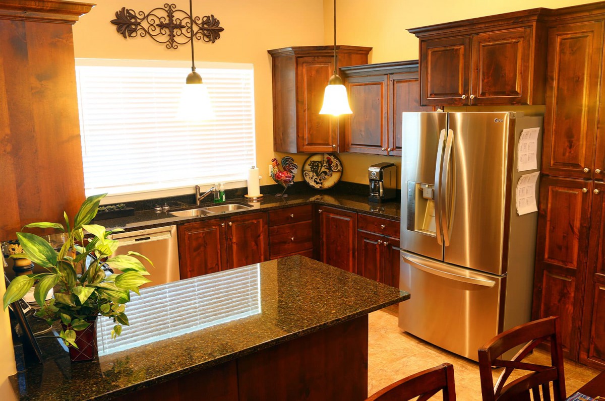 A modern kitchen featuring wood cabinets, a granite countertop, and stainless steel appliances.
