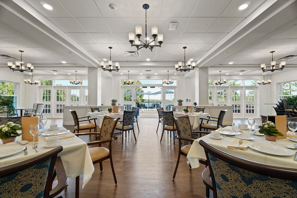 An elegant dining room with neatly arranged tables and chairs, featuring stylish chandeliers and a bright, spacious interior.