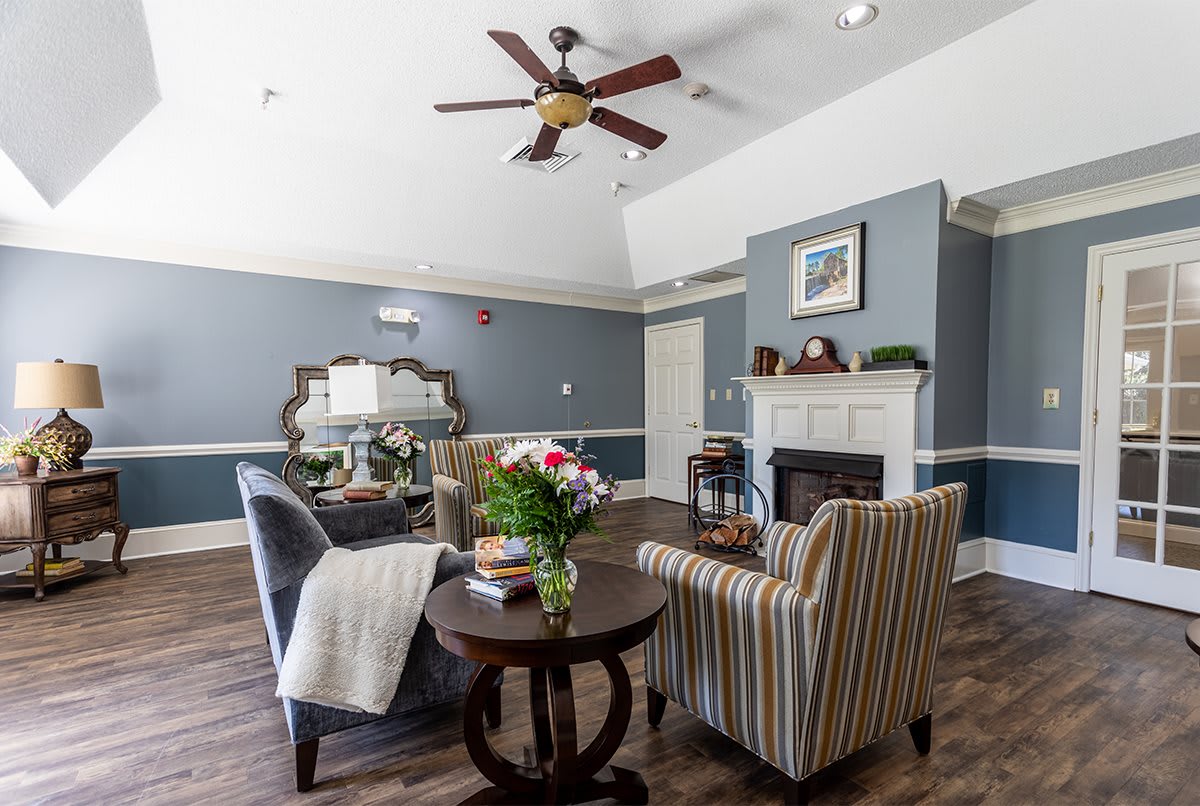 A cozy living room with a fireplace, stylish furniture, and a ceiling fan.