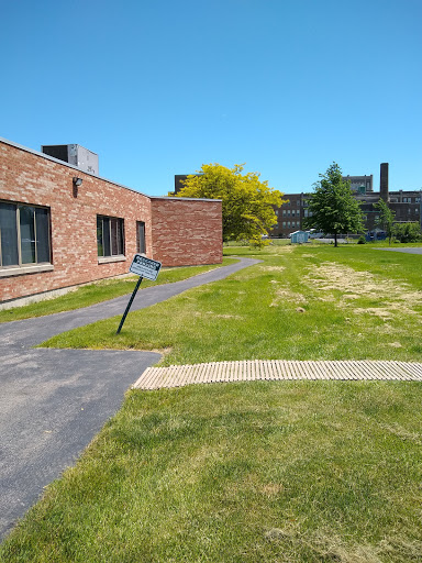 A sunny day showcasing a brick building adjacent to a grassy area with a path leading through it.
