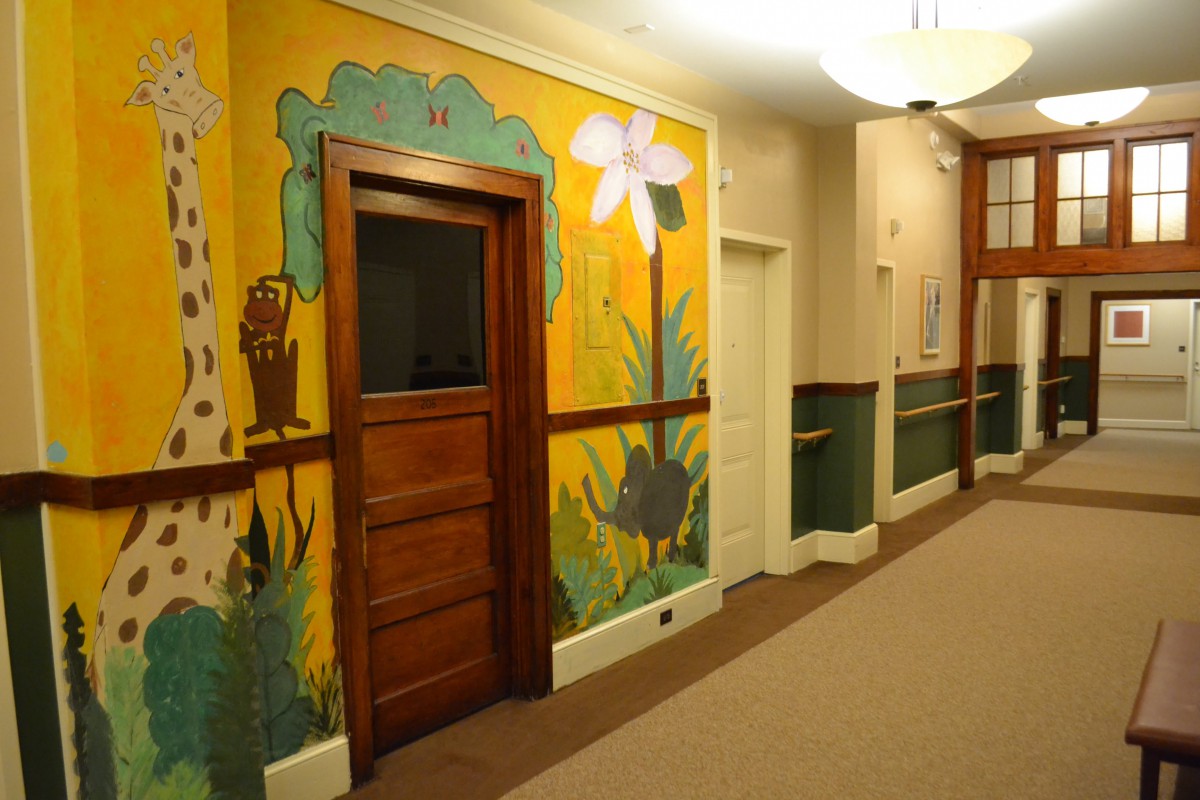 A hallway featuring a colorful mural with a wooden door and decorative elements.