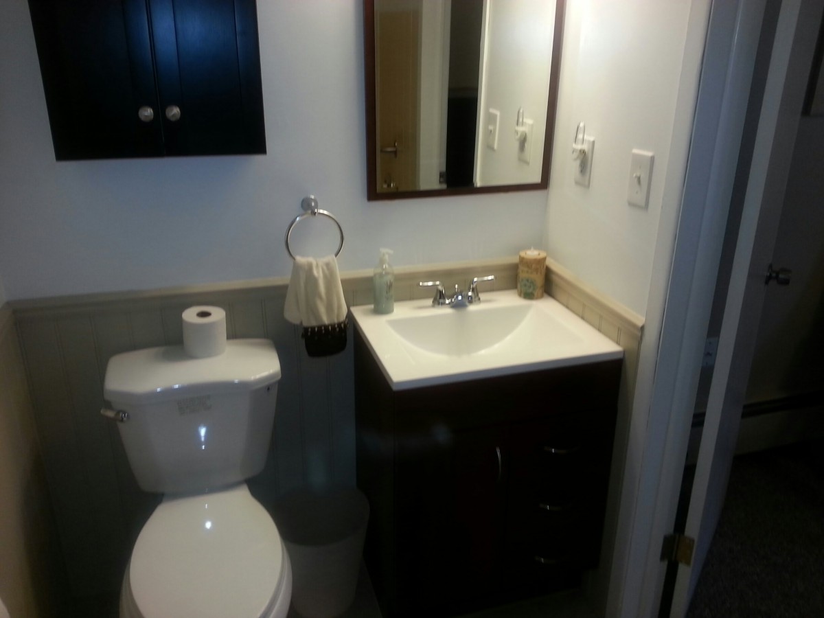 A small bathroom with a toilet, sink, and mirror.