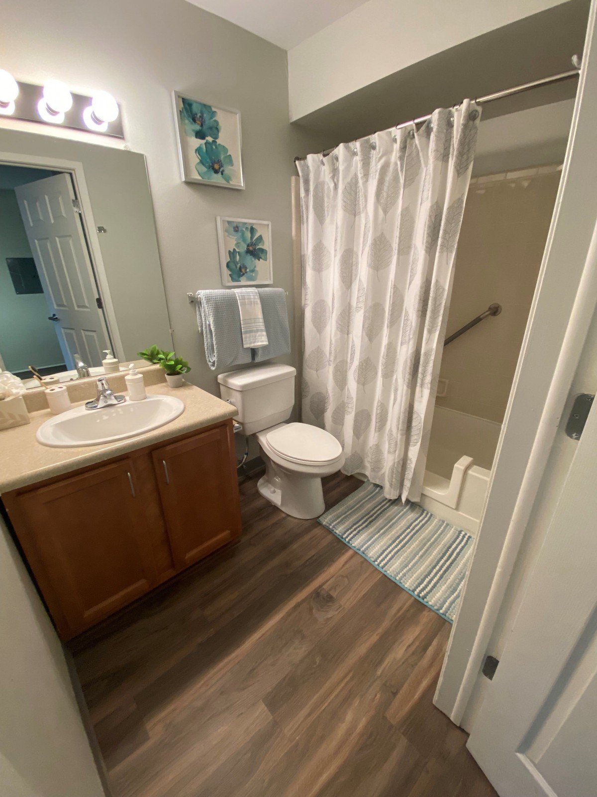 A modern bathroom with wooden cabinetry, a shower area, and decorative elements.