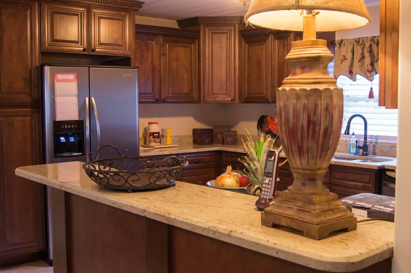 A cozy kitchen setting featuring wooden cabinets and a well-lit countertop with decorative items.