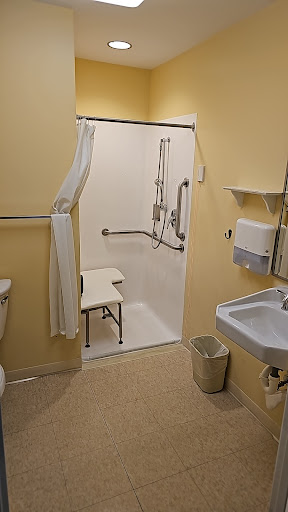 An accessible bathroom equipped with a shower, toilet, and sink.