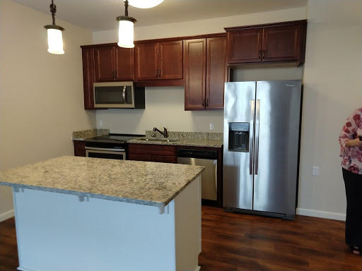 A modern kitchen featuring granite countertops, wooden cabinets, and stainless steel appliances.